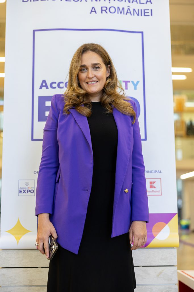 Estera Anghelescu standing in front of a banner saying AccessABILITY Expo - only just seen