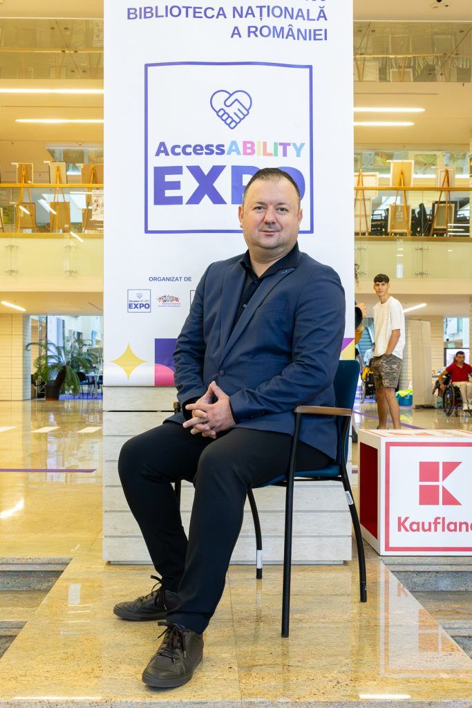 Codrin Scutaru sitting in a chair in front of a banner saying AccessABILITY Expo