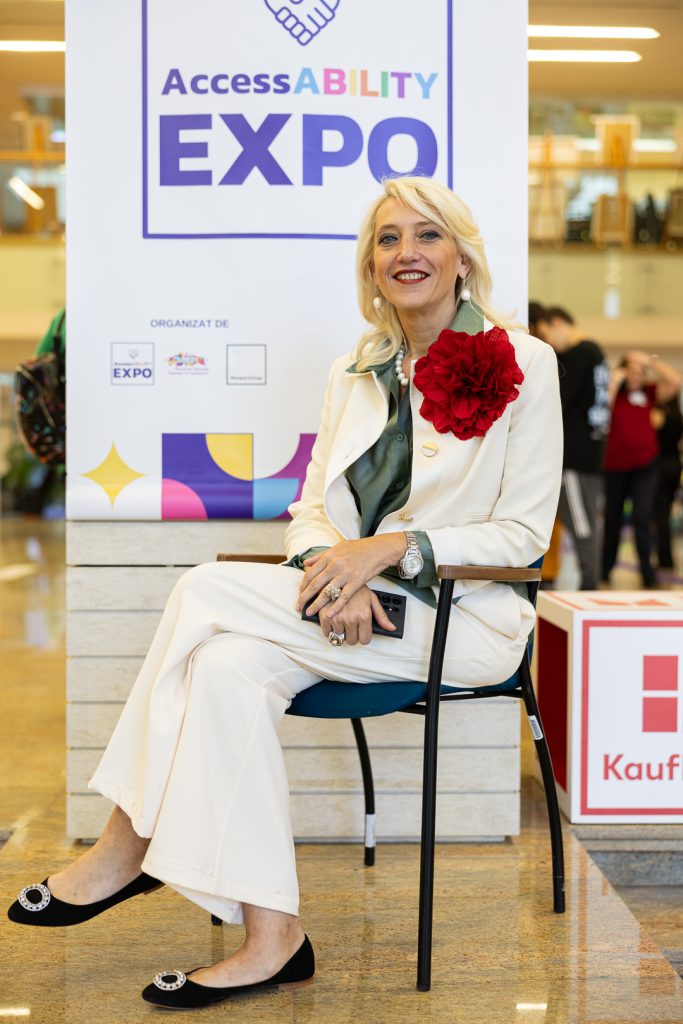 Adela Hanafi sitting on a chair in front of a banner saying AccessABILITY Expo