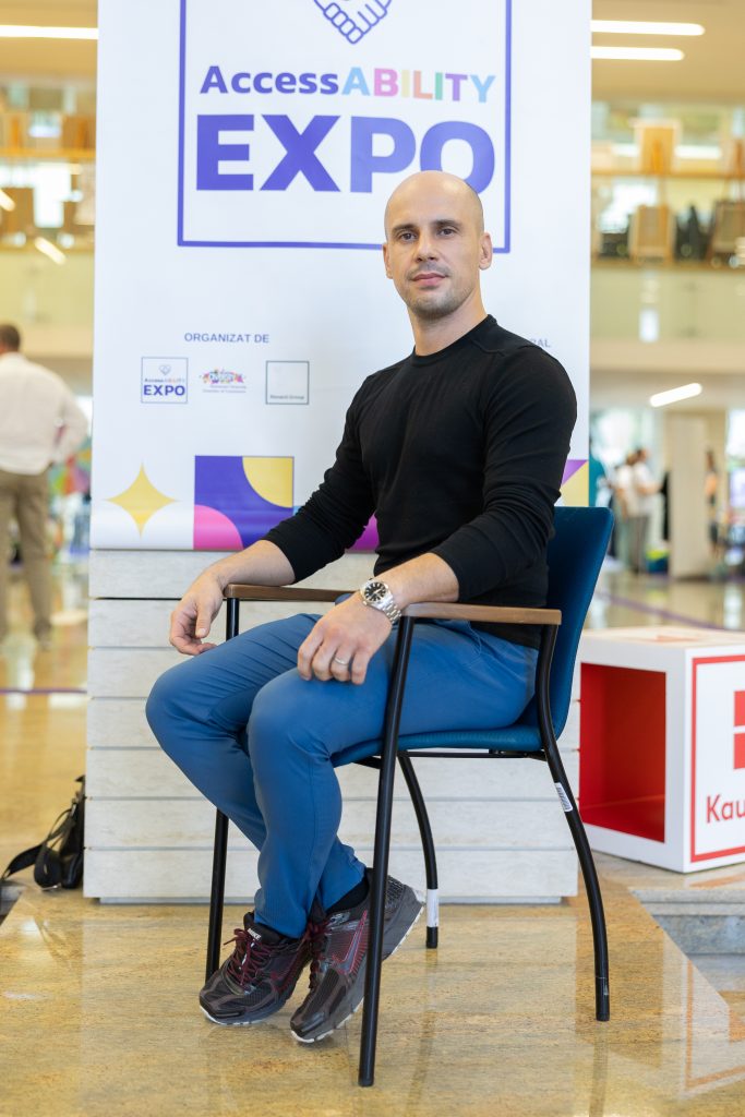 Brad Palas sitting on a chair in front of a banner saying AccessABILITY Expo