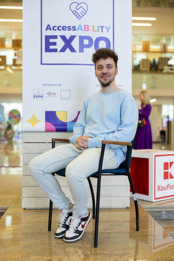 Mihai Cepoi sitting on a chair in front of a banner saying AccessABILITY Expo