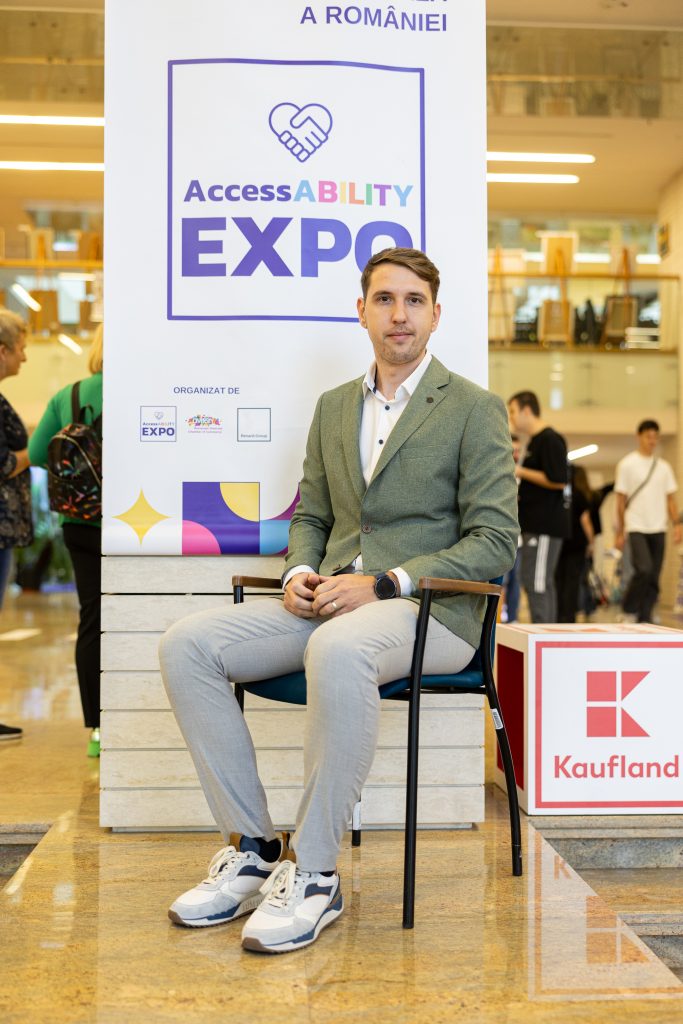 Florin Cirnaru sitting in a chair in front of a banner saying AccessABILITY Expo