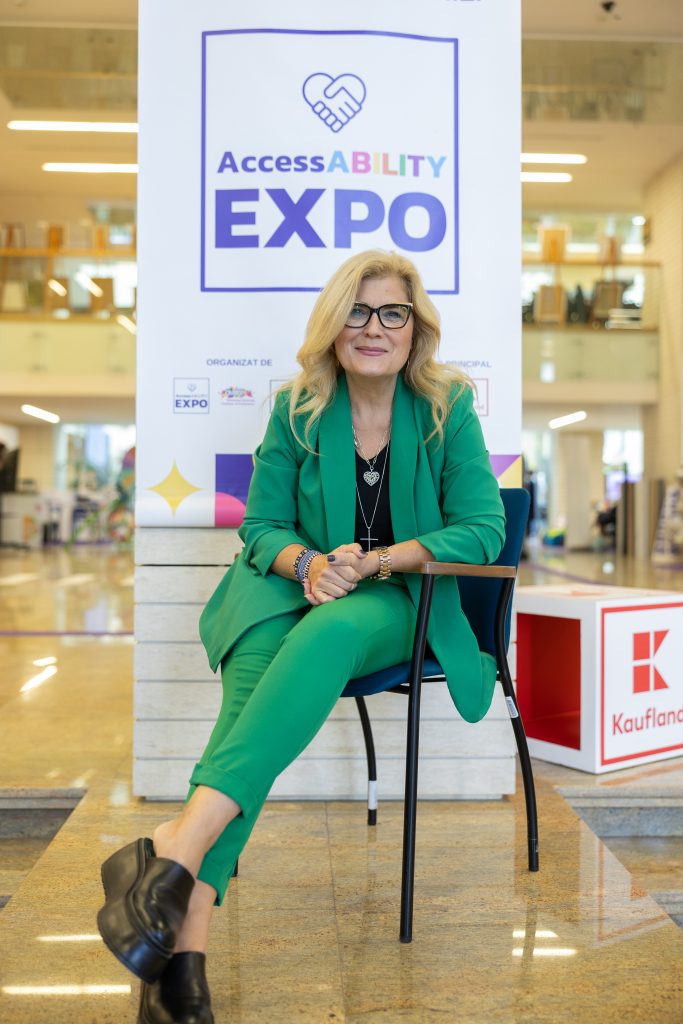 Liana Stanciu sitting on a chair in front of a banner saying AccessABILITY Expo
